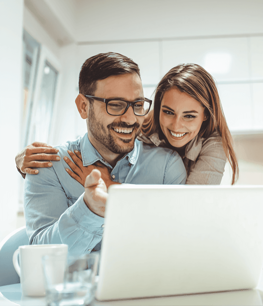 Happy couple using AI content tools together on their laptop from the couch